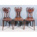 Three George III Mahogany Hall Chairs of American Federal Form, the shield shaped backs with