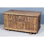 An Old French Oak Coffer, with carved lid, carved and moulded Gothic front, arches and three fleur-