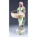A Late 19th/Early 20th Century Continental Pottery Figure of a Nubian Woman, holding an oval basket,