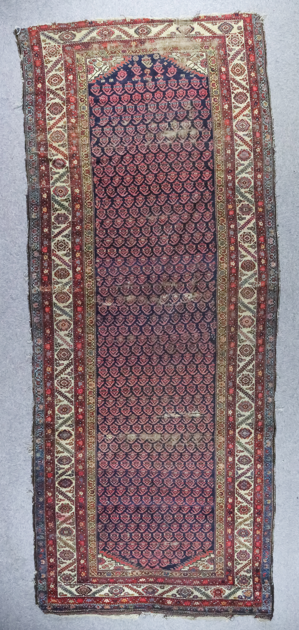 An Antique Fereghan Long Rug, woven in colours, the field filled with twelve rows of hooked boteh on