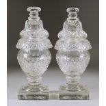 A Pair of Diamond and Slice Cut Glass Urns and Covers, on square bases, 12ins high