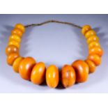 A Moroccan Berber Necklace of nineteen graduated butterscotch amber beads of large proportions,