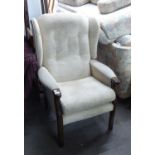 A FIRESIDE ARMCHAIR, COVERED IN CREAM FABRIC