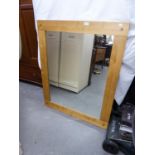 A LARGE RECTANGULAR WALL MIRROR IN BROAD PLAIN WOOD FRAME