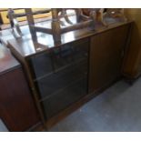 A TEAK SMALL BOOKCASE WITH GLASS SLIDING DOOR AND SLIDING WOOD PANEL DOOR