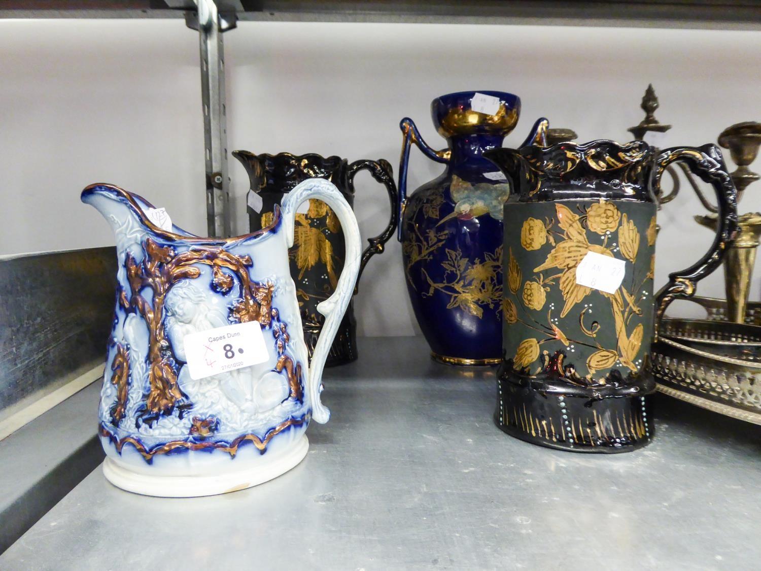 GRADUATED PAIR 'JACKFIELD' BLACK AND GILT POTTERY JUGS, EMBOSSED AND COPPER LUSTRE DECORATED LATE
