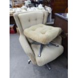 A WINGED EASY ARMCHAIR, REVOLVING ON A METAL FOUR SPUR BASE AND A MATCHING FOOTSTOOL (2)