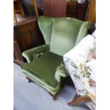 A WINGED FIRESIDE ARMCHAIR, COVERED IN GREEN VELVET