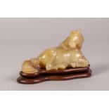 20th CENTURY ORIENTAL CARVED GREEN HARDSTONE model of a recumbent horse on wooden base 5 1/4" (13)