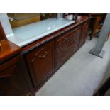 A MAHOGANY LONG LOW SIDEBOARD WITH A NEST OF THREE CENTRE DRAWERS FLANKED BY END CUPBOARDS, ON