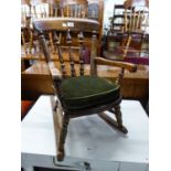 AN EDWARDIAN OAK CHILD'S ROCKING CHAIR, HAVING SPINDLE BACK OVER SOLID SEAT