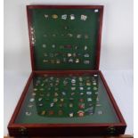 COLLECTION OF 104 SPEEDWAY ENAMELLED METAL BADGES displayed in two glass fronted wooden wall