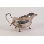 EARLY 20th CENTURY SILVER SAUCE BOAT with cut rim and scroll handle on three authemion capped hoof