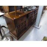 AN OAK ENCLOSED SIDEBOARD WITH ROW OF THREE DRAWERS OVER THREE COFFERED PANEL DOORS, ON PLINTH BASE,