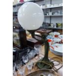 AN ART NOUVEAU STYLE GREEN PATINATED METAL FEMALE FIGURE TABLE LAMP HOLDING UP A WHITE OPAQUE