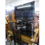 TEVION FLAT SCREEN TELEVISION, 31? WIDE, REMOTE CONTROL, ON A BLACK GLASS THREE TIER STAND AND A