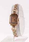 a 9ct GOLD CASED HELVETIA LADY'S WRIST WATCH, on gilt metal linked bracelet