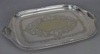 EDWARDIAN ELECTROPLATE ROUNDED OBLONG GADROONED EDGE TWO HANDLED TRAY the centre engraved with an