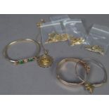 THREE UNMARKED GOLD COLOURED METAL STIFF BANGLES, one set with two cabochon green stones together