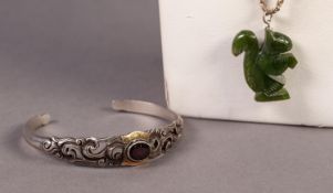 SILVER TORQUE BANGLE pierced with scrolls, the top set with an oval garnet and a carved green