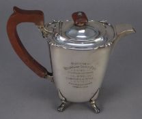 GEORGE VI PRESENTATION SILVER HOT WATER JUG, of rounded oblong form with brown scroll handle and