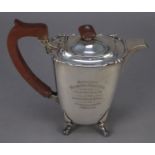 GEORGE VI PRESENTATION SILVER HOT WATER JUG, of rounded oblong form with brown scroll handle and