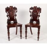 PAIR OF EARLY VICTORIAN CARVED MAHOGANY HALL CHAIRS, each with an ornate back carved with a