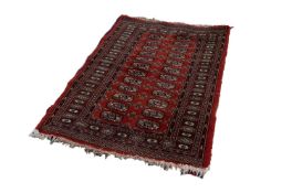 BOKHARA PATTERN EASTERN RUG, with two rows of primary guls on a crimson field, with principal border