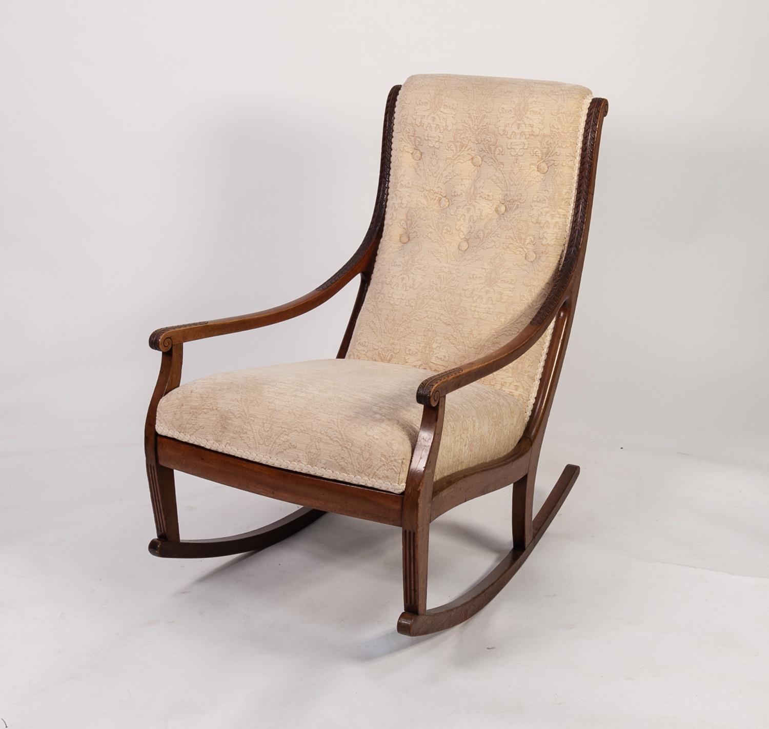 EDWARDIAN MAHOGANY UPHOLSTERED ROCKING CHAIR, the buttoned back flanked by leaf capped downswept