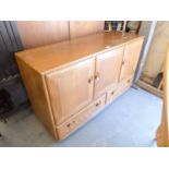AN ERCOL ELM WINDSOR SIDEBOARD, WITH THREE CUPBOARDS ABOVE TWO LONG DRAWERS, RAISED ON CASTORS, (