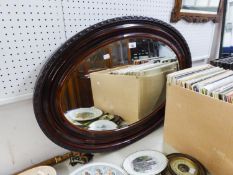 AN OVAL BEVELLED EDGE WALL MIRROR, IN STAINED CAVETTO FRAME