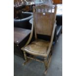 AN EARLY 20TH CENTURY HARD WOOD ROCKING ARMCHAIR WITH PANEL BACK AND SEAT