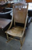AN EARLY 20TH CENTURY HARD WOOD ROCKING ARMCHAIR WITH PANEL BACK AND SEAT