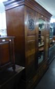 AN EDWARDIAN MAHOGANY INLAID TRIPLE DOOR WARDROBE, WITH CENTRAL MIRROR DOOR, RAISED ON A TWO