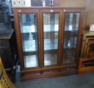 A MAHOGANY DISPLAY CABINET WITH CENTRE GLAZED PANEL, FLANKED BY TWO GLAZED DOORS, ON PLINTH BASE