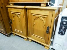 A PAIR OF PINE BEDSIDE CUPBOARDS, EACH WITH ARCH CARVED PANEL DOOR AND METAL RING HANDLES