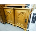 A PAIR OF PINE BEDSIDE CUPBOARDS, EACH WITH ARCH CARVED PANEL DOOR AND METAL RING HANDLES