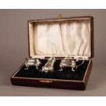 GEORGE V CASED THREE PIECE SILVER CONDIMENT SET, of bellied form with cyma borders and scroll