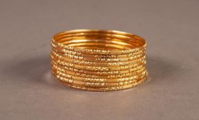 SET OF 10 NARROW BANGLES with chased decoration, 2 1/4" (5.7cm) diameter, (stamped 22ct), 79.2gms,