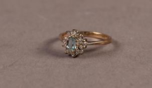 CLUSTER RING set with a centre oval aquamarine and surround of ten small brilliant cut round