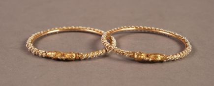 PAIR OF BANGLES, each terminating in two animal's heads, the bangles spirally fluted and bound
