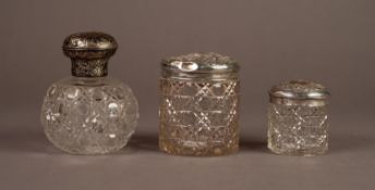 THREE VICTORIAN AND LATER CUT GLASS CONTAINERS WITH EMBOSSED SILVER COVERS, comprising: an ORBICULAR