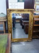 A LARGE MODERN OBLONG BEVELLED EDGE WALL MIRROR, IN PERIOD STYLE, LARGE FOLIATE EMBOSSED GILT FRAME,