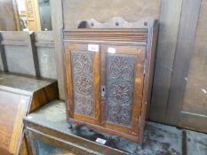 AN EARLY TWENTIETH CENTURY OAK SMOKERS CABINET HAVING CARVED PANEL DOORS