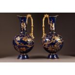 PAIR OF LATE NINETEENTH CENTURY OLD HALL POTTERY EWERS, each of footed form with moulded gilt handle