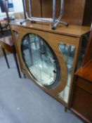 A WOOD EFFECT DISPLAY CABINET WITH GLASS SLIDING DOORS TO THE CIRCULAR FRONT APERTURE