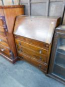 AN OAK BUREAU WITH THREE LONG DRAWERS BELOW