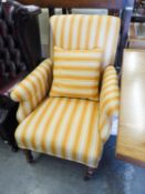AN ANTIQUE ARMCHAIR, COVERED IN STRIPED FABRIC, RAISED ON TURNED SUPPORTS