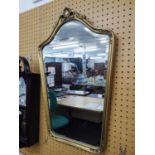 A BEVELLED EDGE WALL MIRROR, CARTOUCHE SHAPED, IN EMBOSSED GILT FRAME