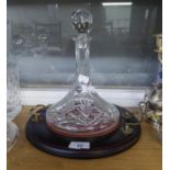 A STERLING HAND CUT CRYSTAL SHIP?S DECANTER, ON MAHOGANY CIRCULAR TWO HANDLED TRAY STAND